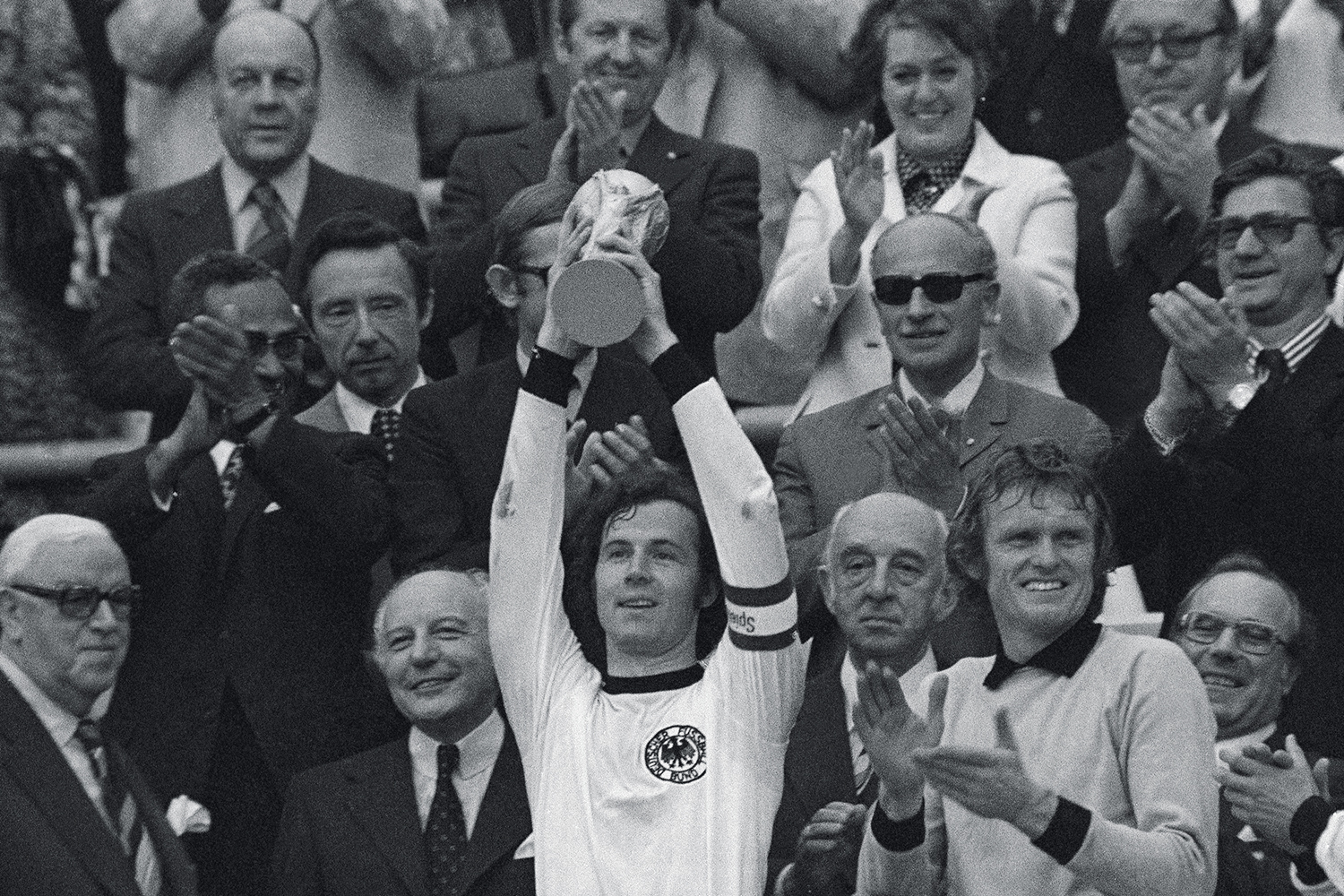 FILE - In this July 7, 1974 file photo, West Germany captain, Franz Beckenbauer, holds up the World Cup trophy after his team defeated the Netherlands by 2-1, in the World Cup soccer final at Munich's Olympic stadium, in West Germany. Applauding at right, German goalkeeper Josef 