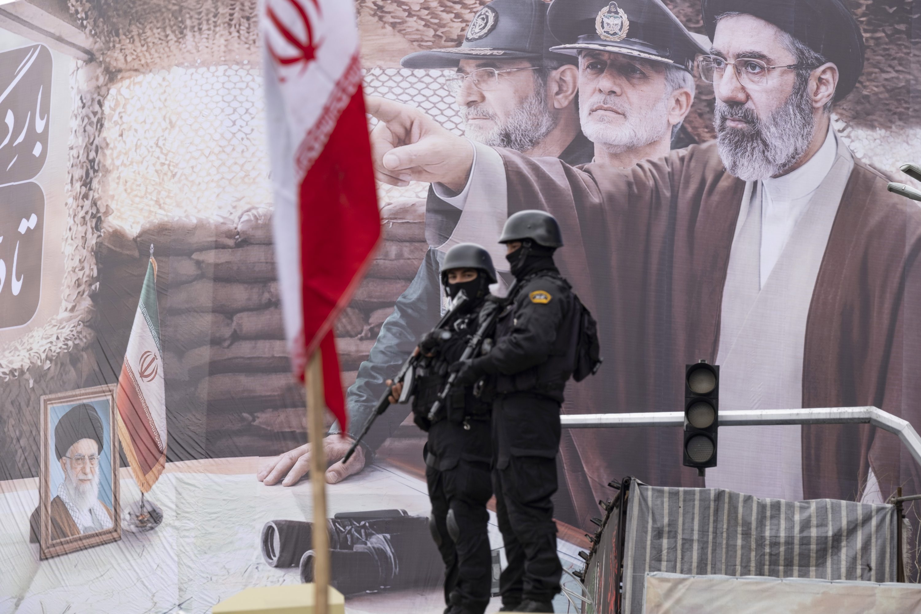 Guardas armados em frente a uma foto do novo líder supremo do Irã, Mojtaba Khamenei (13/03/2026)